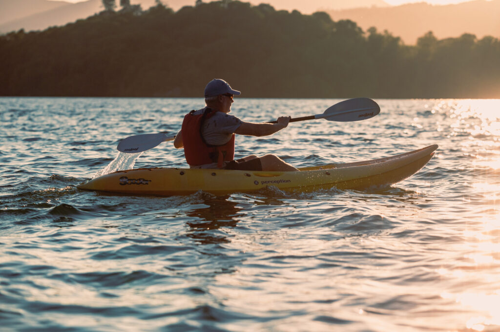 Adult male kayaking on Windermere lake at sunset on a summers day